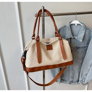 Détail du sac de voyage en toile avec poignées en cuir marron et bandoulière réglable