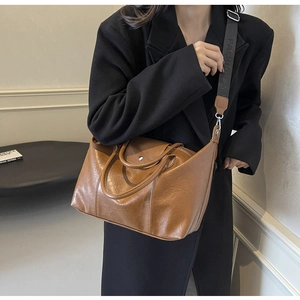 Brown faux leather tote bag with wide fashion strap shown in a minimalist lifestyle setting