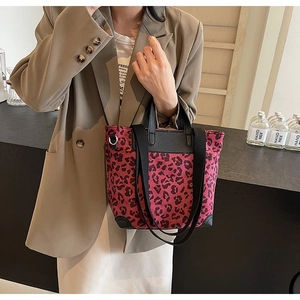 Red leopard print tote bag with black leather handles and adjustable crossbody nylon strap