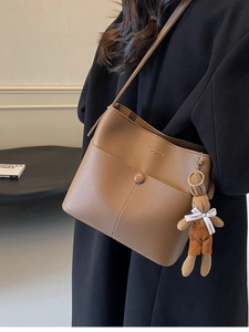 Brown litchi leather bucket bag with cute rabbit charm shown on a fashion model