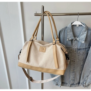 Détail du grand sac de voyage en toile et cuir suspendu sur un rack en métal