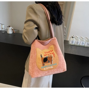 Dettaglio della borsa tote in velluto a coste rosa corallo con ricamo gatto giallo
