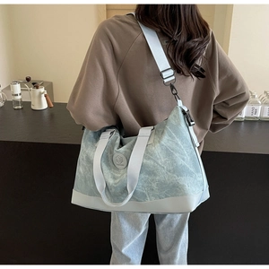 Detail of light blue washed canvas travel bag with round logo on a cafe background