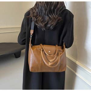 Detail view of brown pebbled leather tote bag with wide strap on model