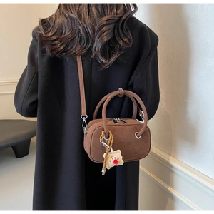 Petit sac bandoulière en cuir dépoli marron avec breloque ours porté par un mannequin