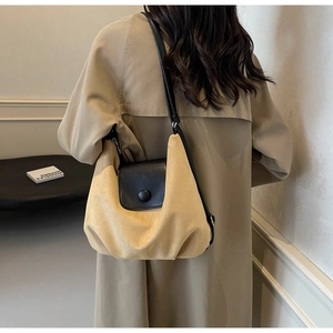 Detailed back view of a large khaki hobo tote bag worn with a trench coat in a minimalist setting