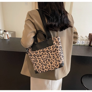 Detail of leopard print tote bag with black leather trim and woven shoulder strap