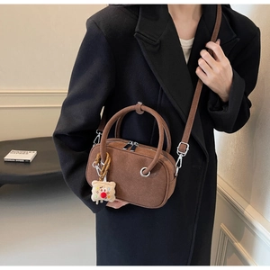 Détail du sac bandoulière en daim marron foncé avec poignée anneau et breloque ours