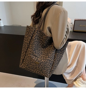 Detailed view of leopard print canvas tote bag styled on model in modern office setting