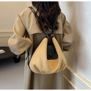 Detailed back view of a yellow suede backpack with black leather straps on a khaki trench coat