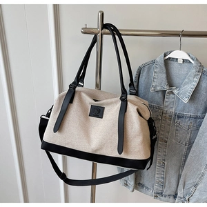 Détail d'un grand sac de voyage en toile avec poignées noires et écusson logo