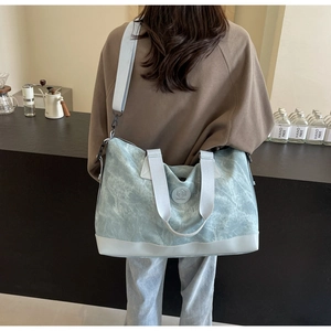 Detail of light blue marble pattern travel tote with adjustable shoulder strap and leather base