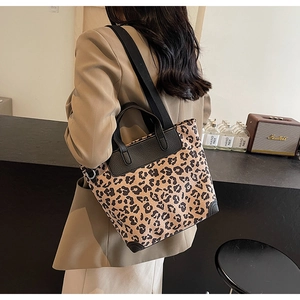 Leopard print tote bag with black leather trim and wide textile strap shown on model