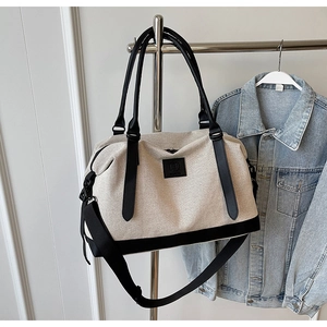 Détail d'un sac de voyage en toile avec lanières en cuir et plaque logo sur un portant