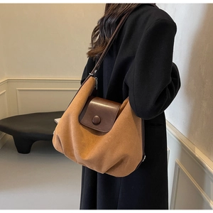 Detail of a brown suede tote bag featuring a leather flap and large round button closure