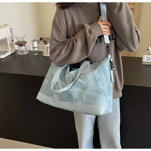 Detail of light blue canvas travel bag with marble texture and leather reinforced bottom