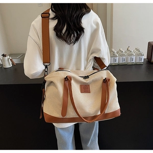 Vue détaillée du canevas beige et des lanières en cuir marron du sac de voyage cabas