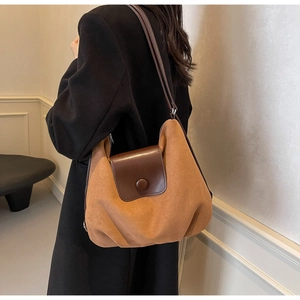 Detail view of the brown suede and leather patchwork tote bag on a black winter coat