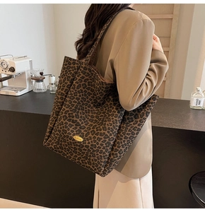 Close-up of leopard print velvet tote bag with gold logo plaque on a shoulder strap