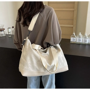 Woman carrying a large off-white canvas travel bag with leather base in a cafe
