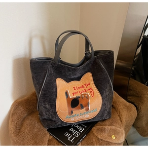 Dettaglio della borsa tote in velluto a coste grigio con patch gatto e manici in pelle