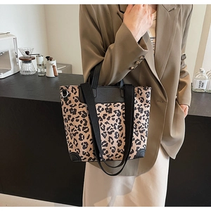 Detailed view of leopard print tote bag with black leather handles and reinforced base