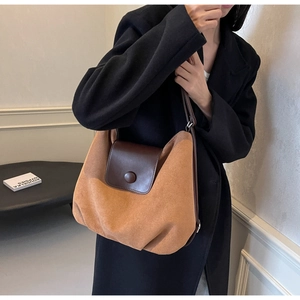 Detail of camel suede tote bag with brown leather flap and round snap closure on model