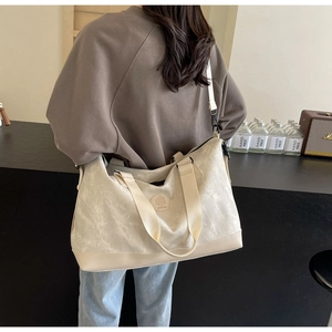 Detail of a large off-white canvas travel tote with reinforced base and adjustable strap