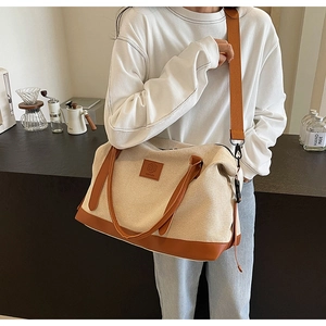 Vue détaillée du sac de voyage en toile et cuir avec bandoulière et doubles poignées