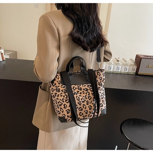 Detail of leopard print tote bag with black leather trim and wide straps on a model