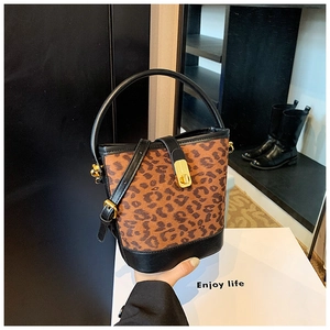 Detail of leopard print bucket bag featuring black leather trim and golden clasp buckle