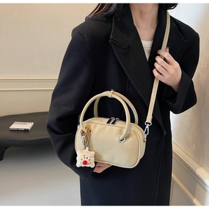 Détail du sac bandoulière beige en daim givré avec fermeture argentée et charme peluche