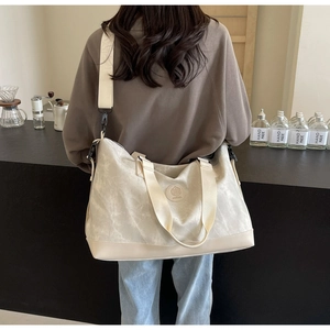 Back view of a model carrying a large marble pattern travel tote with adjustable strap