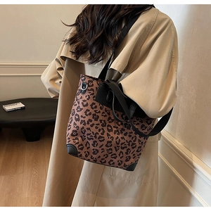Close-up of leopard print tote bag with black leather trim and adjustable shoulder strap