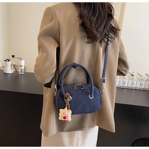 Détail du sac à bandoulière bleu foncé givré avec zips argentés et breloque ours