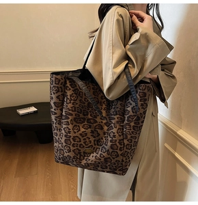 Detail of leopard print tote bag with metal plaque worn with khaki trench coat