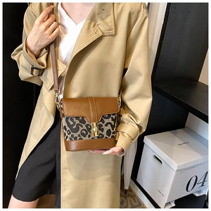 Detail of leopard print canvas and brown leather crossbody bucket bag with gold clasp