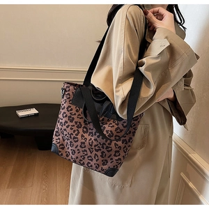 Detailed view of leopard print tote bag with black leather corners and wide shoulder strap