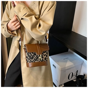 Detail view of leopard print bucket bag with brown leather flap and gold twist lock