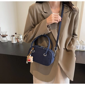 Détail du sac en daim bleu marine avec doubles poignées et pendentif ours en peluche