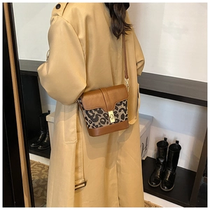 Detail of a leopard print bucket bag with gold clasp worn with a beige trench coat