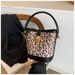 Detail of leopard print bucket bag with gold hardware and black leather base on books