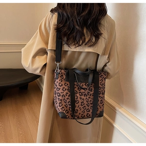 Detailed view of the leopard print tote bag with black leather straps on a khaki trench coat