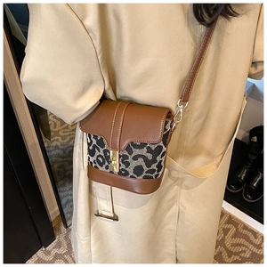 On-body shot of a mini leopard print crossbody bag with metal lock and brown leather strap