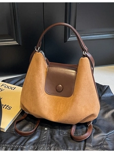 Brown suede tote backpack with leather straps shown on leather background