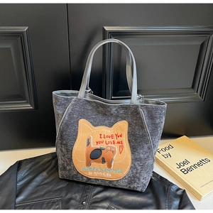 Dettaglio della borsa tote in tessuto grigio con toppa ricamata a forma di gatto sul davanti