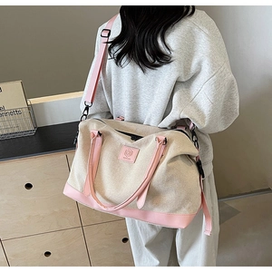 Détail d'un grand sac de voyage en toile avec bordure rose et bandoulière ajustable