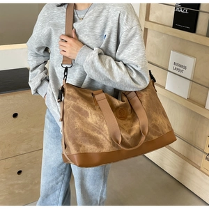 Brown vintage travel bag made of washed canvas and faux leather worn by a model