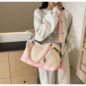 Détail du grand sac de voyage en toile avec lanières en cuir rose et bandoulière réglable