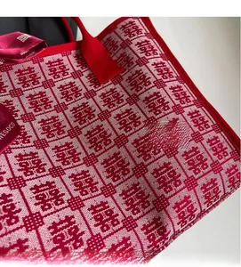 Detail of red wedding tote bag featuring woven Xi character and silk ribbon bow